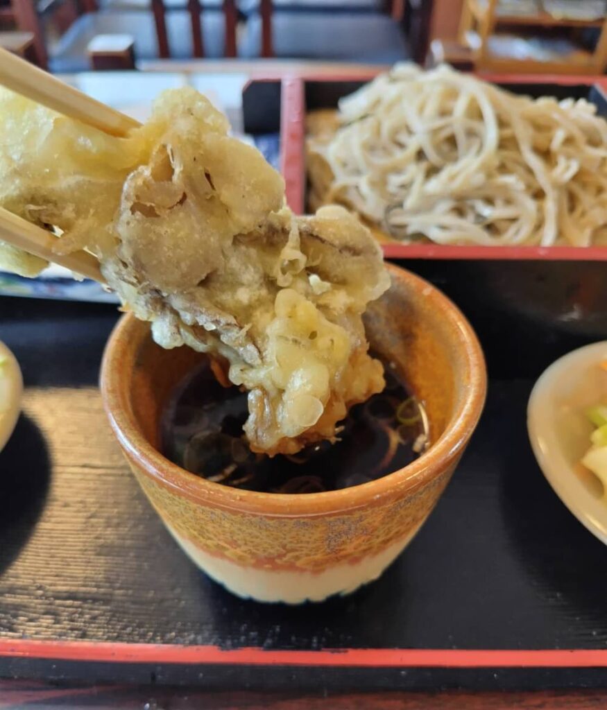 舞茸天をざるそばの汁に付けてたべる写真