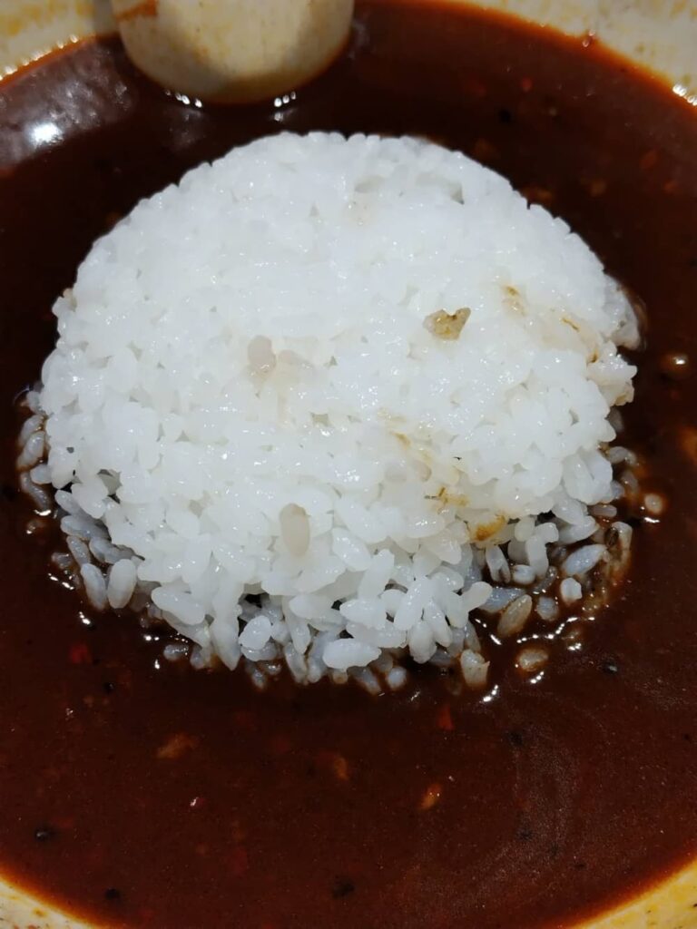 黒磯駅から徒歩4分の「たんたん亭」で「激辛担々麺」のスープにライスを投入している写真