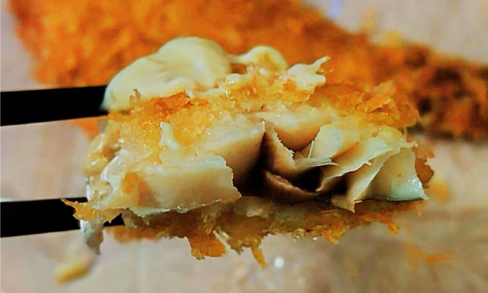 アジフライにタルタルソースをかけて食べる様子