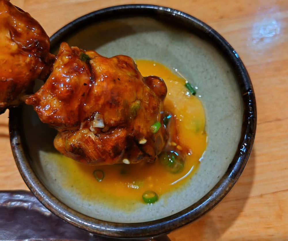 つくねを卵黄に付けている様子