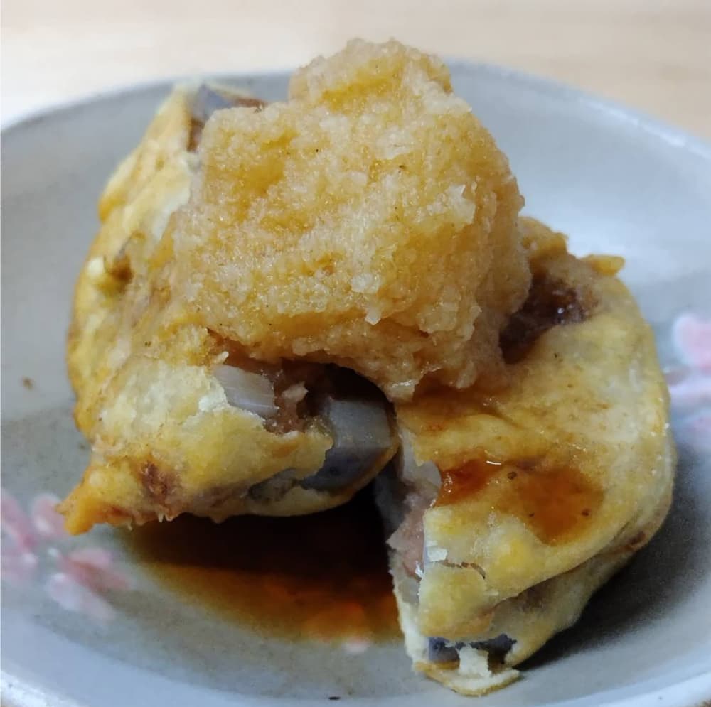 レンコンのはさみ揚げの上に大根おろしが乗り、そこへポン酢がかかっている写真