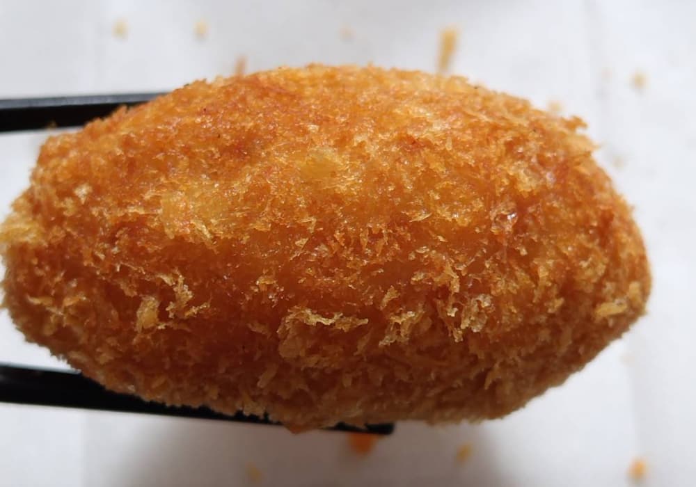 チーズインメンチカツを箸で持ち上げている写真